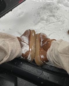 someone's feet covered in snow on top of a car