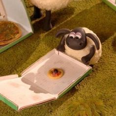 a toy sheep is eating a donut in a box