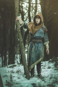 a man dressed in medieval clothing standing next to a tree