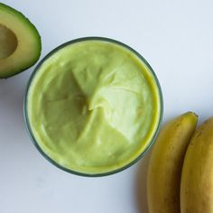 an avocado and banana are next to a glass filled with green smoothie