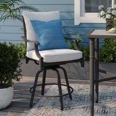 a chair with a blue pillow sitting on top of it next to a table and potted plant