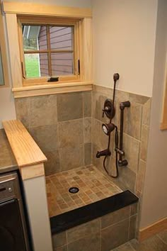 a bathroom with a shower, sink and window in it's corner stall next to a washer and dryer