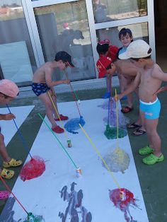 several children are painting on a large sheet of paper