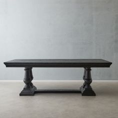 a black table sitting on top of a cement floor next to a wall with a plant in it