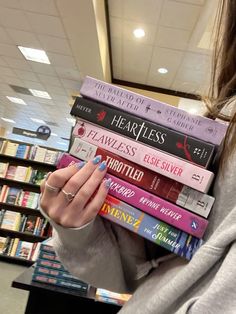 a woman holding a stack of books in front of her face