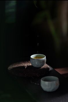 a white bowl filled with liquid sitting on top of a wooden table next to two bowls