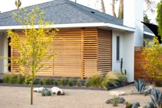 a modern house with wood slats on the front and side walls, surrounded by landscaping