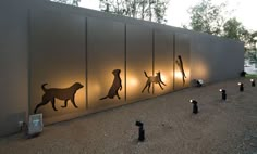 the silhouettes of people and dogs are lit up on the side of a building