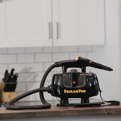 a black and yellow steam iron sitting on top of a wooden counter next to white cabinets