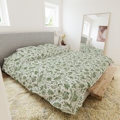 a bed with a green and white bedspread in a bedroom next to a mirror