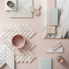 marble and ceramic items are arranged on a pink surface, including a bowl, cup, napkins, and other decorative objects