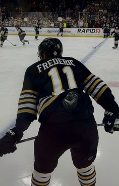 an ice hockey player on the ice with his stick in hand and people watching from the stands behind him