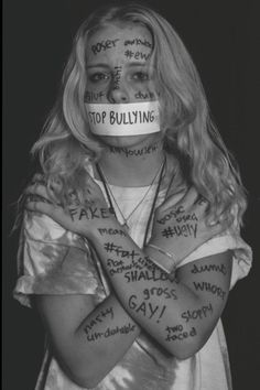 a woman with her arms crossed and words painted on her face in front of her