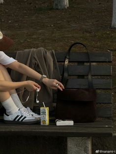 a woman is sitting on a bench with her handbag and keys in her other hand