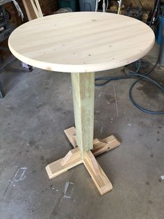 a round wooden table sitting on top of a floor next to a pile of wood