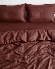 an unmade bed with red sheets and pillows