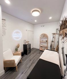 a room with white walls and wood floors, including a bed in the center surrounded by plants