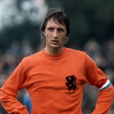 a man in an orange shirt standing with his hands on his hips