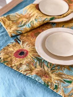 the table cloth has sunflowers on it, and is set with white plates