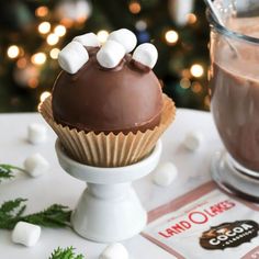 there is a cupcake with marshmallows on it and a glass of hot chocolate