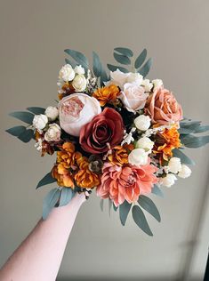 a hand holding a bouquet of flowers in it's left arm, with leaves on the top