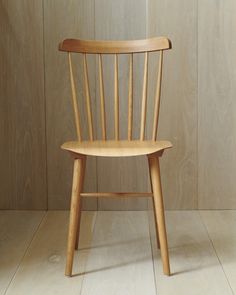 a wooden chair sitting on top of a hard wood floor next to a white wall