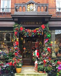 a store front decorated with colorful flowers and greenery on the outside, including wreaths