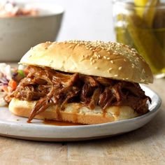 a pulled pork sandwich sitting on top of a white plate