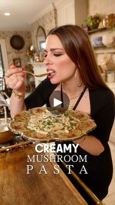 a woman eating food from a plate on top of a wooden table in a kitchen