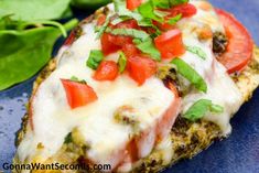 a piece of bread with tomatoes and cheese on it next to some spinach leaves