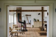 an open door leading to a living room with chairs and a stove in it's center