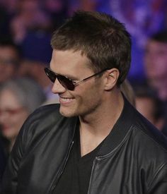 a man wearing sunglasses is smiling for the camera while standing in front of an audience