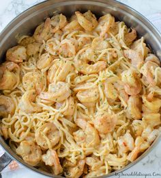 a pan filled with pasta and shrimp on top of a table