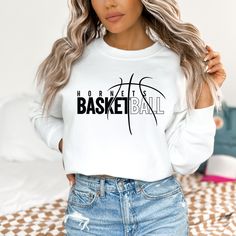 a woman wearing a white sweatshirt with the words basketball on it