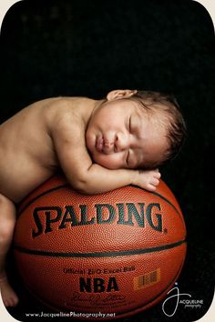 a baby sleeping on top of a basketball