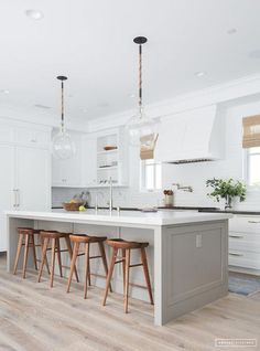 a kitchen with white cabinets and wooden stools next to an island in the middle