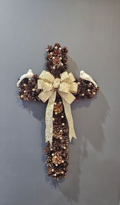 a cross made out of pine cones and bows