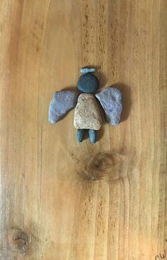 a stone angel sitting on top of a wooden table next to a blue and white teddy bear