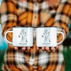 two people holding coffee mugs with the letters s i and l on them in their hands