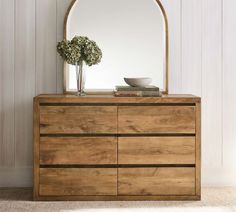 a wooden dresser with a mirror and vase on top