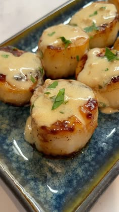 some scallops covered in sauce on a blue plate