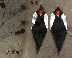 two pairs of black and white beaded earrings with red, yellow, and white wings