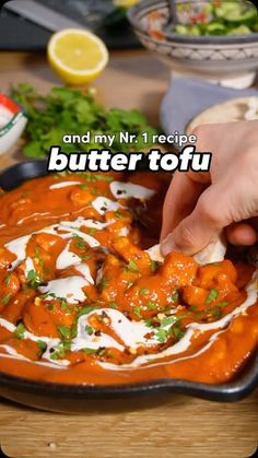 a person dipping sauce on top of food in a black bowl with the words butter tofu above it