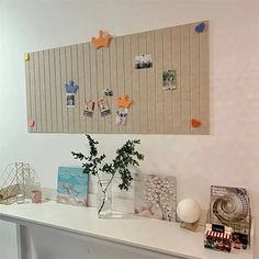 a white table topped with vases filled with flowers and pictures next to a wall mounted bulletin board