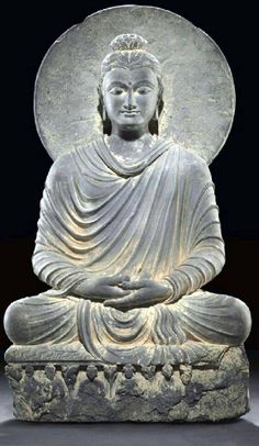 a buddha statue sitting on top of a stone block