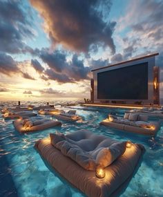 an outdoor movie is set up in the water at sunset with lounge chairs and pillows