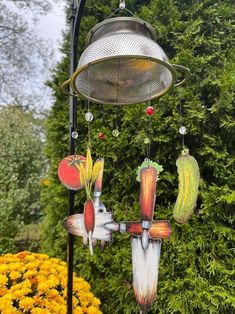 a wind chime hanging from the side of a pole next to flowers and trees