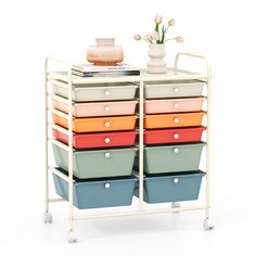 a multicolored storage cart with six drawers and a flower vase on top, against a white background