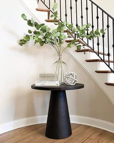 there is a vase with some flowers on the table in front of the stair case