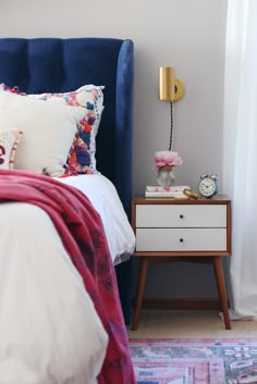 a bedroom with a blue headboard and white bedding, two nightstands on either side